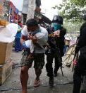 epa04044207 A Filipino father carries his daughter as elite policemen from the Special Weapons And Tactics (SWAT) fire tear gas during a demolition of shanties at Sitio San Roque along Agham Road in Quezon City, east of Manila, Philippines, 27 January 2014. Throwing rocks, pillboxes, and even human waste, illegal settlers barricaded the demolition team in Agham Road Sitio San Roque in Baranggay Bagong Pag-asa. Four residents were arrested and twelve were reported injured. Residents report receiving cash from US$300-450 in exchange for their voluntary relocation. Earlier, hundreds of the urban poor marched to the city hall in protest of the demolition that will pave the rise of a business district.Thousands of families living near Agham Road in Quezon City's North Triangle are reportedly targeted for demolition to make way for construction of a commercial district, local media reports stated. EPA/DENNIS M. SABANGAN