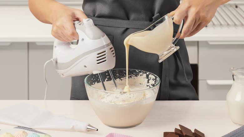 Person using electric hand mixer