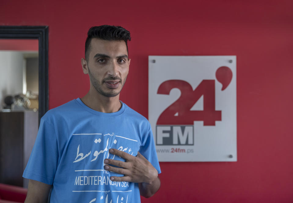 Palestinian journalist Akil Awawdeh poses for a portrait at his office in the West Bank city of Ramallah, Wednesday, July 14, 2021. Nearly two weeks after he was severely beaten by Palestinian security forces, Awawdeh is still short of breath, still shielding his bruised chest with his hand and still haunted by the screams inside the police station. (AP Photo/Nasser Nasser)