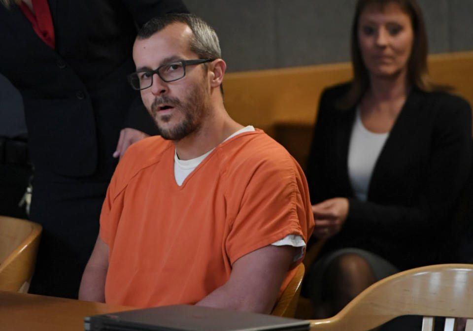 Watts in an orange prison outfit seated in a courtroom