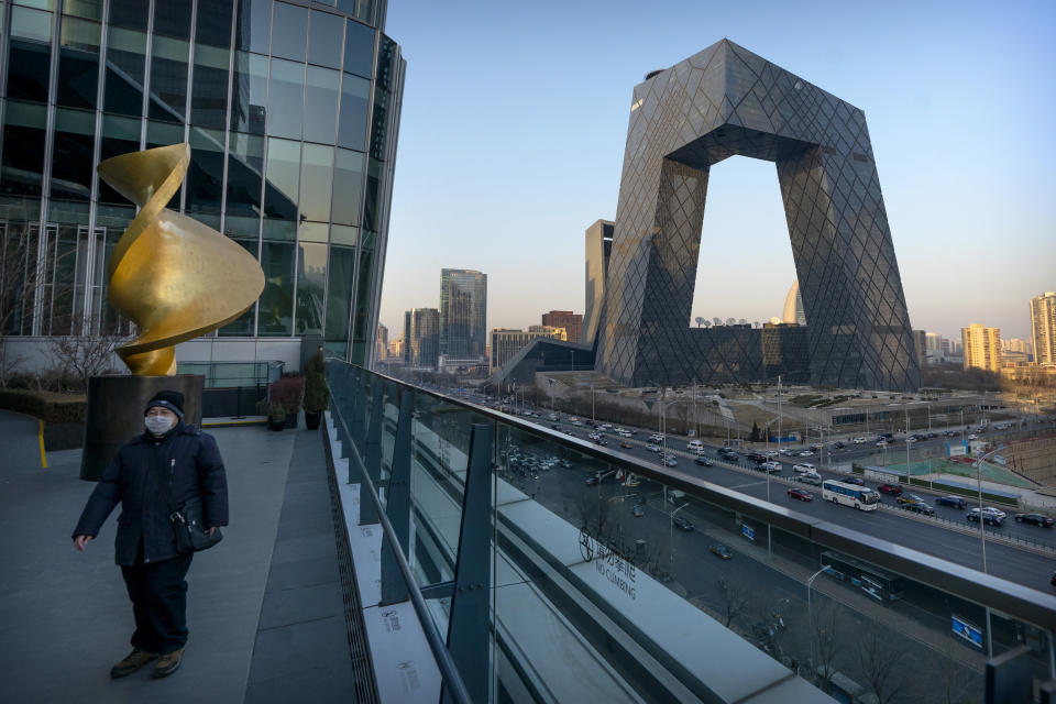 FILE - In this Feb. 4, 2021, file photo, a man wearing a face mask to protect against the spread of the coronavirus walks along an observation deck near the CCTV Headquarters building, the home of Chinese state-run television network CCTV and its overseas arm CGTN, in Beijing. China has banned the BBC World News television channel from the few outlets where it could be seen in the country in possible retaliation after British regulators revoked the license of state-owned Chinese broadcaster CGTN. (AP Photo/Mark Schiefelbein, File)