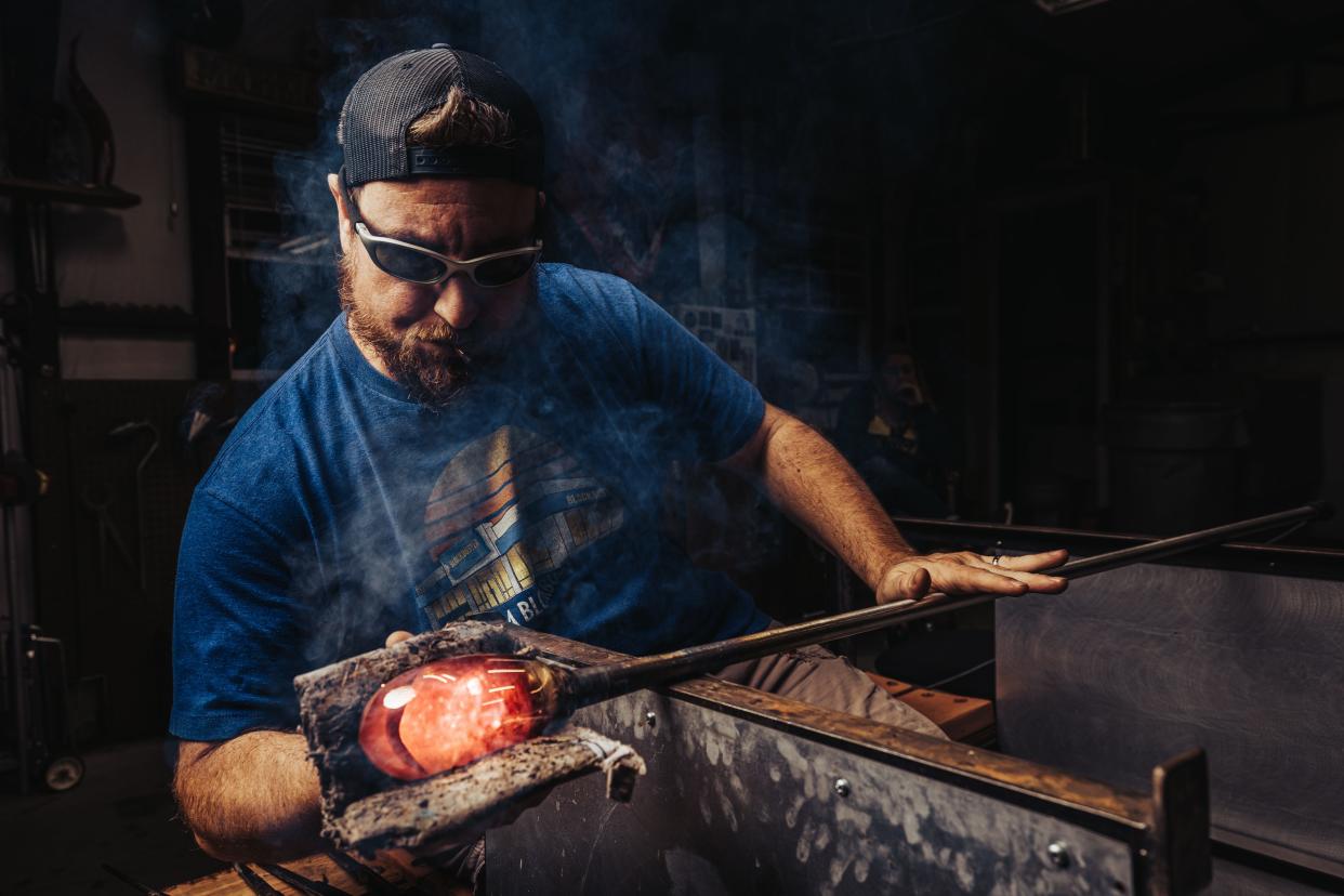 Erich Minton uses damp newspaper to shape glass.