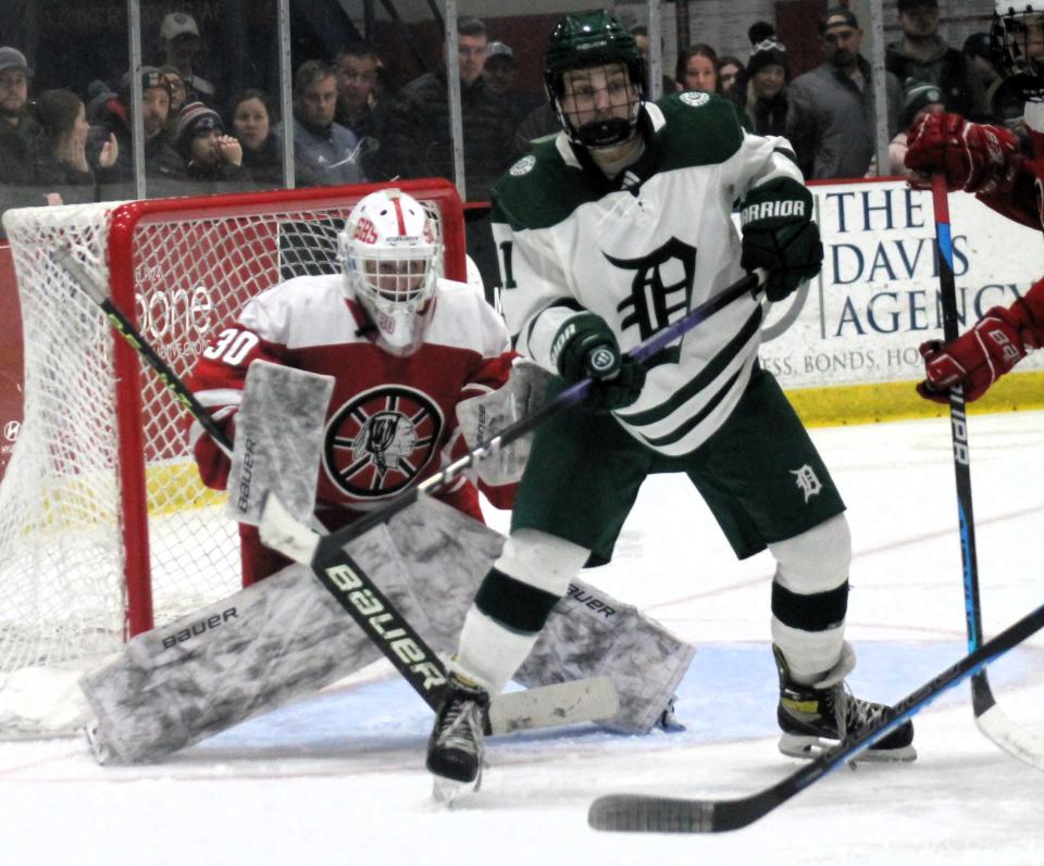 Dover's Grant Davis tries to screen Spaulding goalie Collin McIntyre (30) during the Red Raiders' semifinal win over the Green Wave on Wednesday, March 6, 2024 at Everett Arena in Concord.