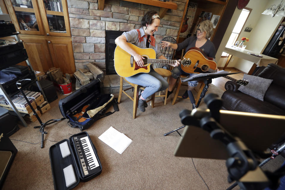 In this May 22, 2020, photo, nurse Megan Palmer, left, and care partner Anna Henderson, who both work at Vanderbilt University Medical Center, appear during a songwriting session at Henderson's home in Ashland City, Tenn. During the COVID-19 pandemic, their role as caregivers has become even more important as hospital visits from family and friends were limited or prohibited to prevent the spread of the virus. Music and songwriting has helped them express the complexity of emotions that comes with caregiving, especially in the time of a pandemic. (AP Photo/Mark Humphrey)