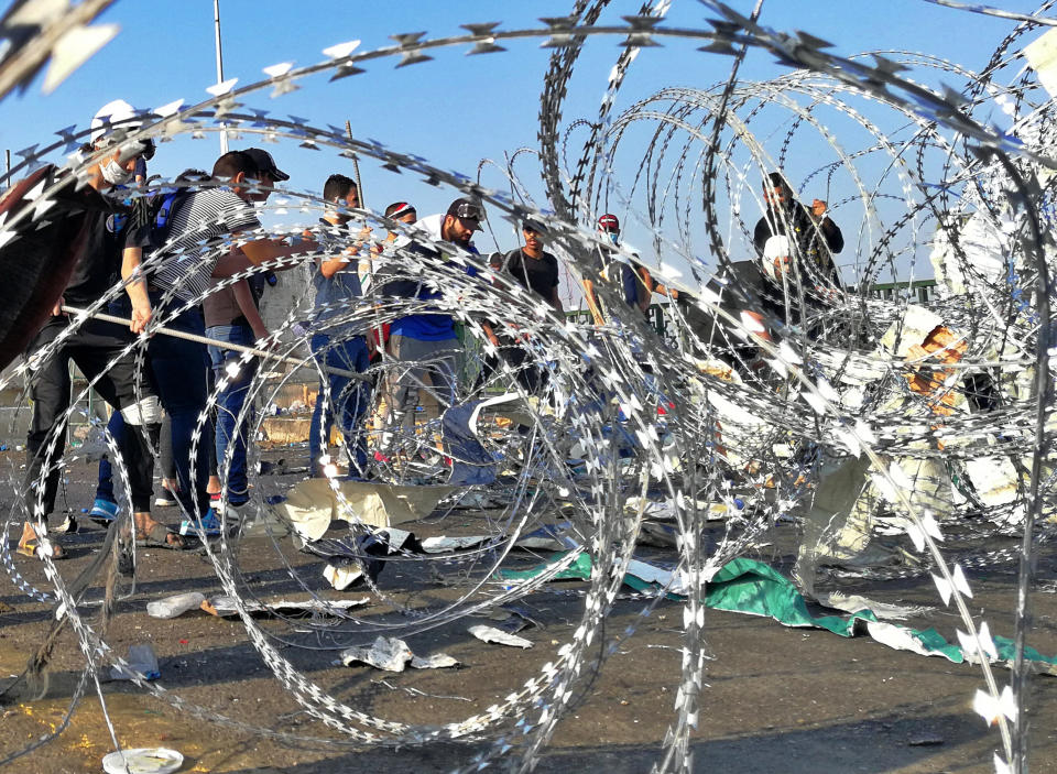 Iraqi anti-government protesters remove barriers set by security forces to close the Al-Sanak Bridge leading to the Green Zone during a demonstration in Baghdad, Iraq, Thursday, Oct. 31, 2019. Late Wednesday, hundreds of people headed to the Al-Sanak Bridge that runs parallel to the Joumhouriya Bridge, opening a new front in their attempts to cross the Tigris River to the Green Zone. Security forces fired volleys of tear gas that billowed smoke and covered the night sky. (AP Photo/Khalid Mohammed)