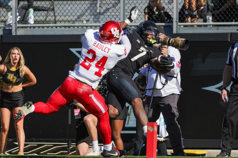 UCF Knights running back RJ Harvey (7) is pushed out of bounds by Houston Cougars defensive back Adari Haulcy (24) during the second half at FBC Mortgage Stadium.