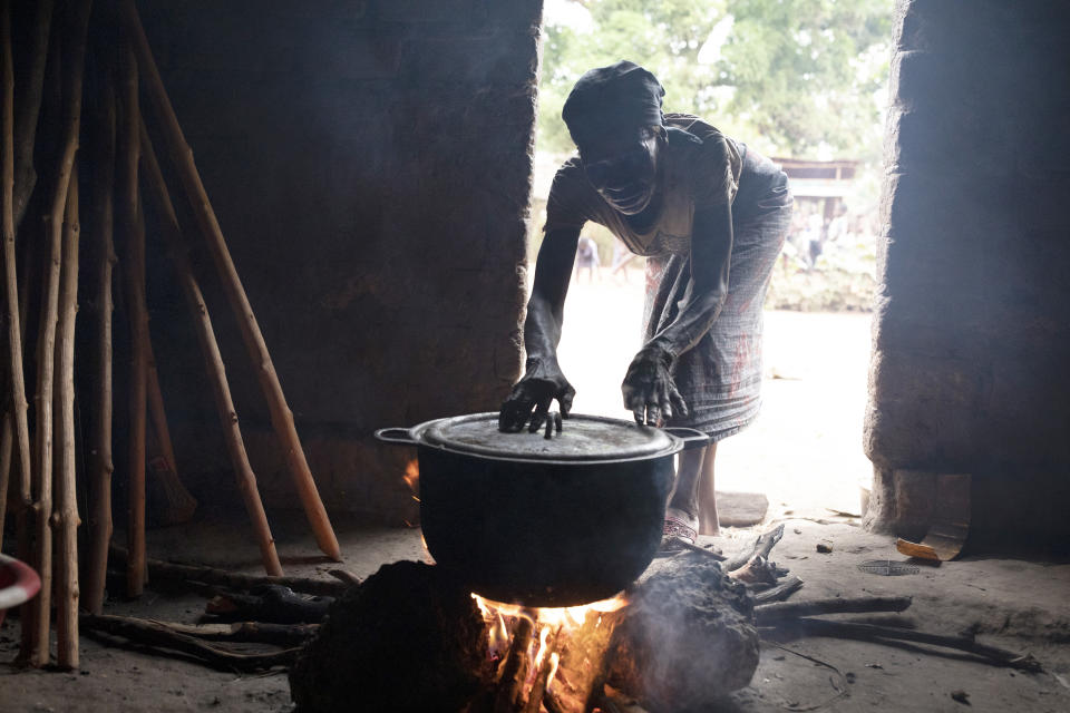 Nana Mputsu recolecta restos de madera de una propiedad que quemaron para convertirla en tierras de cultivo, en Mbandaka, República Democrática del Congo, el 15 de marzo de 2022. (Ashley Gilbertson/The New York Times)