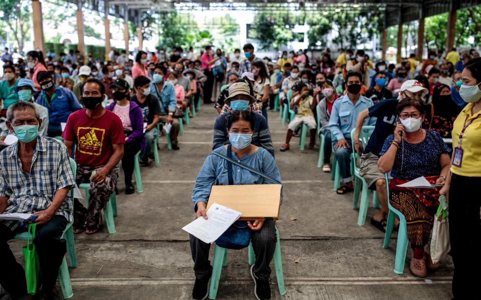 People wear face masks as they queue outside Public Relations Department to register complaints for not having received 5000 baht (around $150) meant to provide assistance to those effected by COVID-19 coronavirus in Bangkok Thailand on May 12, 2020. - Jack Taylor 