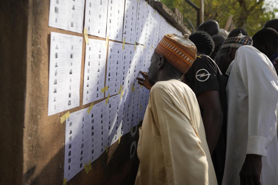 People check voters' lists before casting their ballots during the presidential and parliamentary elections in Yola, Nigeria, Saturday, Feb. 25, 2023. Voters in Africa's most populous nation are heading to the polls Saturday to choose a new president, following the second and final term of incumbent Muhammadu Buhari. (AP Photo/Sunday Alamba)