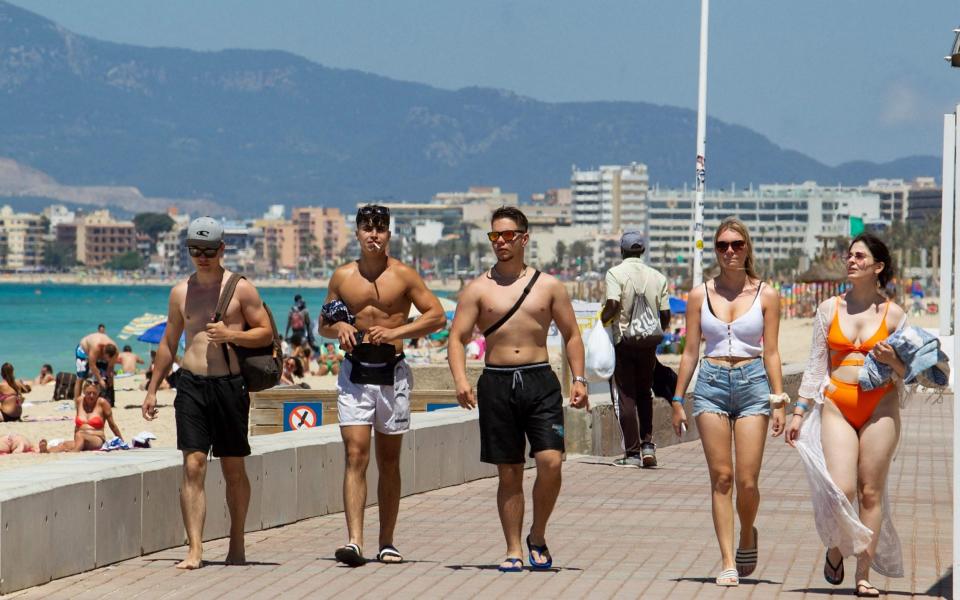 Tourists walk on the promenade at Palma Beach in Palma de Mallorca - JAIME REINA/AFP