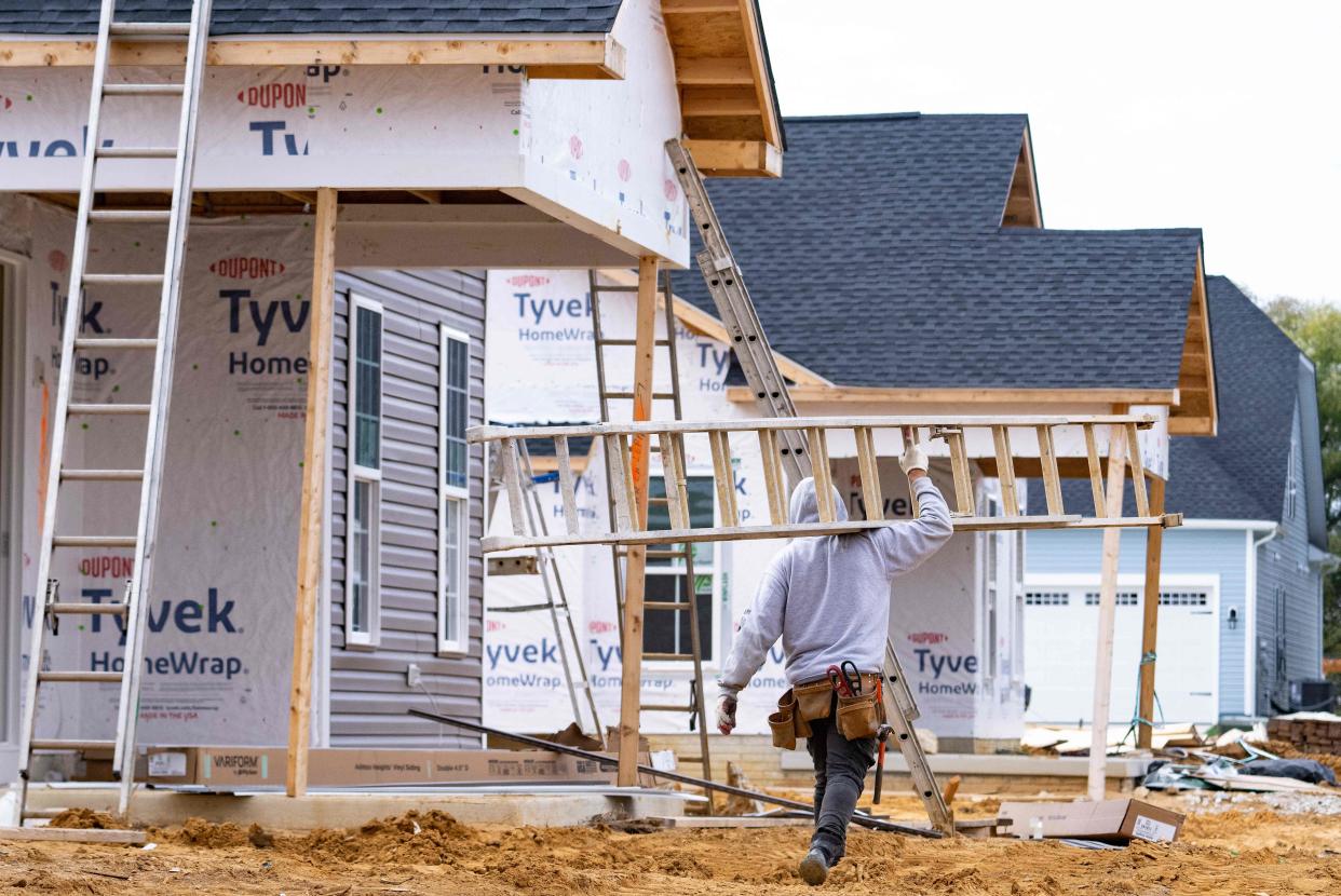 A man carries a ladder through new home construction in Trappe, Maryland. (Credit: Jim Watson, AFP via Getty Images)