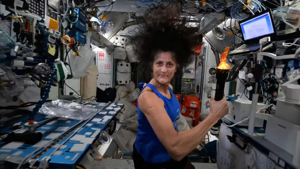 Suni Williams holds a fake torch in a space station module