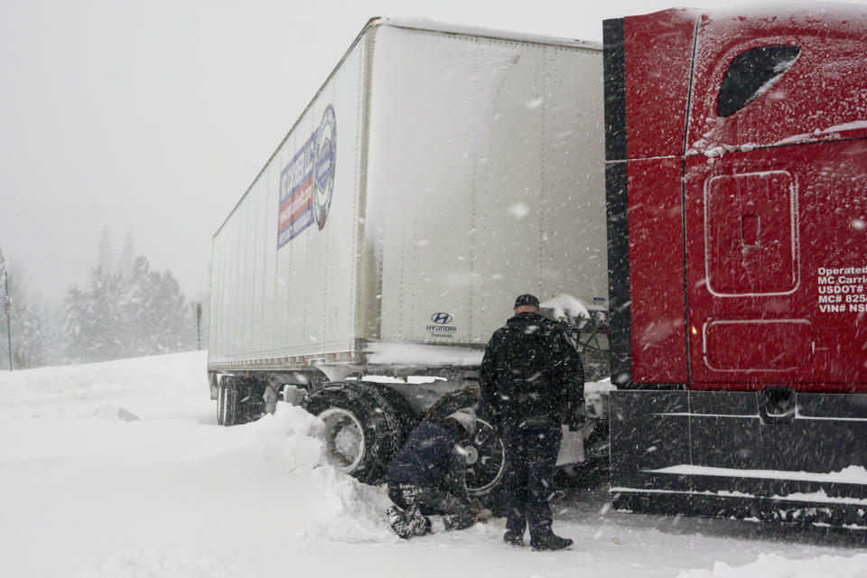Chains are installed on a big rig's tires during a storm, Saturday, March 2, 2024, in Truckee, Calif. A powerful blizzard howled Saturday in the Sierra Nevada as the biggest storm of the season shut down a long stretch of Interstate 80 in California and gusty winds and heavy rain hit lower elevations, leaving tens of thousands of homes without power. (AP Photo/Brooke Hess-Homeier)