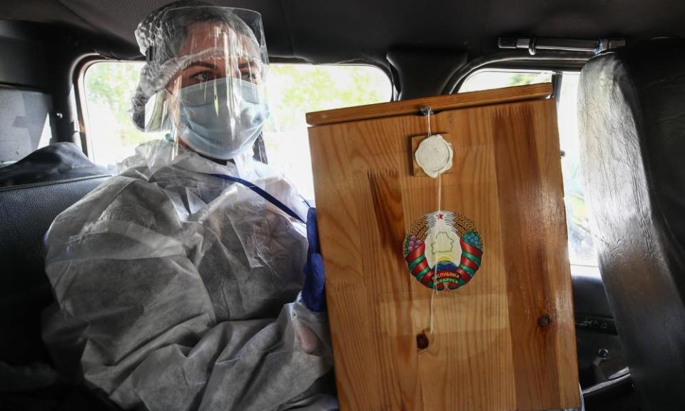 An election commission member holds a ballot box in a car before home voting.