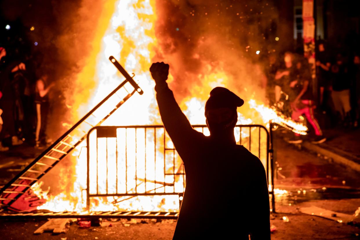 A protester raises a fist near a fire during a demonstration outside the White House over the death of George Floyd at the hands of Minneapolis Police in Washington, DC, on May 31, 2020. (Samuel Corum/AFP via Getty Images)