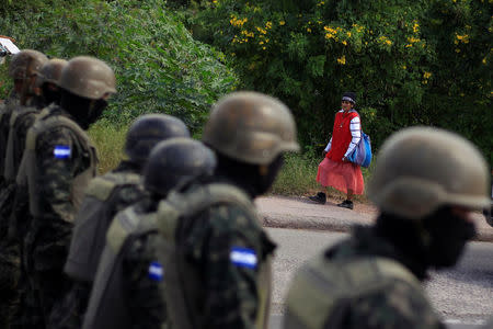 A woman walk pass a check point as soldiers guard the city after the Honduras government enforced a curfew on Saturday while still mired in chaos over a contested presidential election that has triggered looting and protests in Tegucigalpa, Honduras December 2, 2017. REUTERS/ Jorge Cabrera