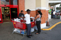 Jamaicans stand next to shopping carts filled with bottled water and other items outside a supermarket, pending the arrival of Hurricane Matthew in Kingston, Jamaica, September 30, 2016. REUTERS/Gilbert Bellamy