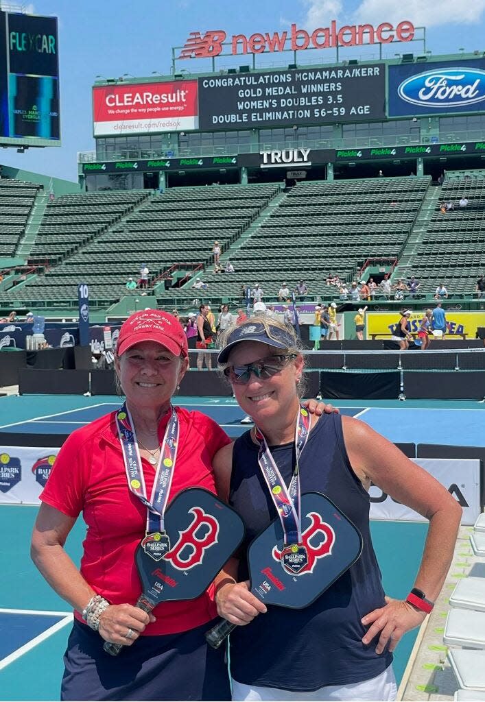 With their championship win listed on the scoreboard in the background, Sudbury's Christine McNamara, left, poses with Lynn Kerr after they won their division at the Pickle4 Ballpark Series at Fenway Park on July 12.