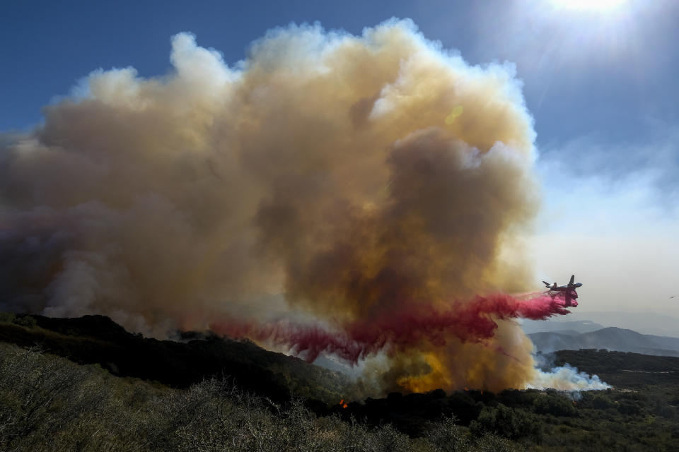 An air tanker drops retardant on a wildfire Wednesday, Oct. 13, 2021, in Goleta, Calif. A wildfire raging through Southern California coastal mountains threatened ranches and rural homes and kept a major highway shut down Wednesday as the fire-scarred state faced a new round of dry winds that raise risk of flames. The Alisal Fire covered more than 22 square miles (57 square kilometers) in the Santa Ynez Mountains west of Santa Barbara. (AP Photo/Ringo H.W. Chiu)