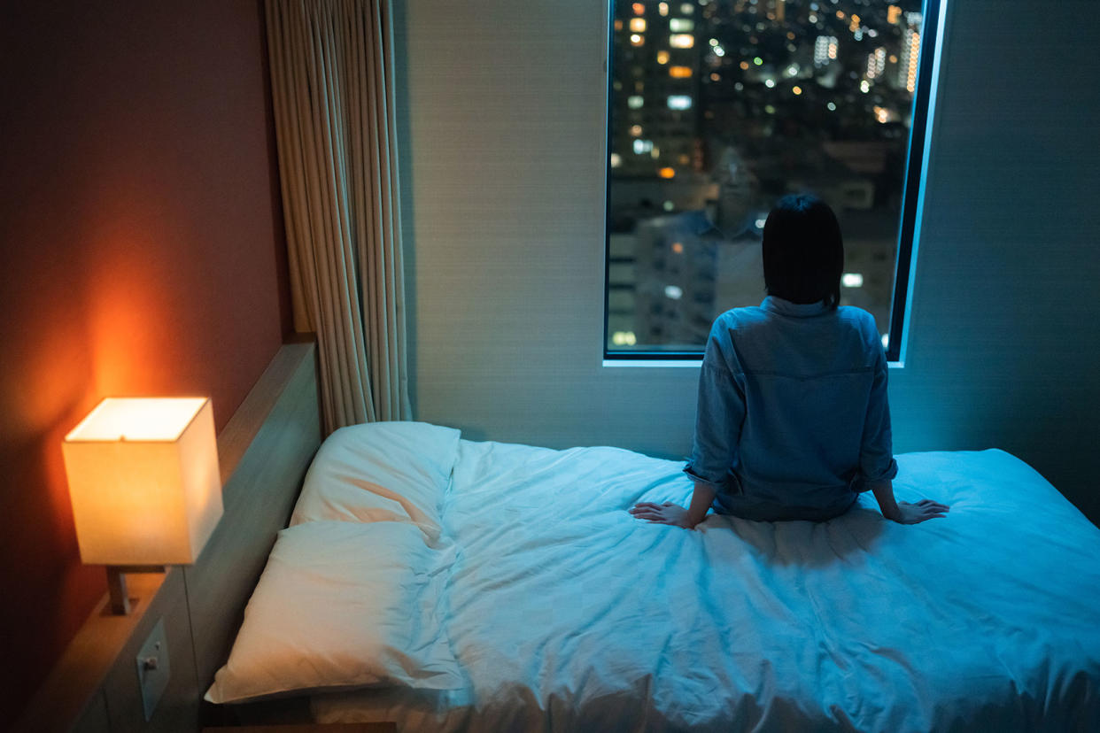 woman sitting in bed awake looking out window night insomnia Getty Images/recep-bg