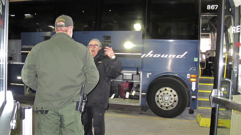 In this Thursday, Feb. 13, 2020 photo, a worker, right, speaks with a Customs and Border Protection agent seeking to board a Greyhound bus headed for Portland, Ore., at the Spokane Intermodal Center, a terminal for buses and Amtrak in Spokane, Wash. A Customs and Border Protection memo obtained by The Associated Press confirms that bus companies such as Greyhound do not have to allow Border Patrol agents on board to conduct routine checks for illegal immigrants, contrary to Greyhound's long insistence that it has no choice but to let the agents on board. (AP Photo/Nicholas K. Geranios)