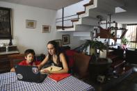 In this March 20, 2020 photo, Nadia Muñoz helps her son Luka with his online lessons from a private Catholic school, at their home in an upper-middle-class neighborhood of Lima, Peru. For the makeup artist and her family, Lima's near-total 15-day quarantine hasn’t been too disruptive. (AP Photo/Martin Mejia)