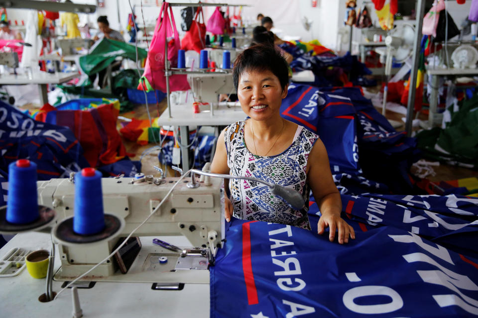 A worker poses for pictures as she makes flags meant to promote U.S. President Donald Trump's "Keep America Great!" 2020 re-election campaign.