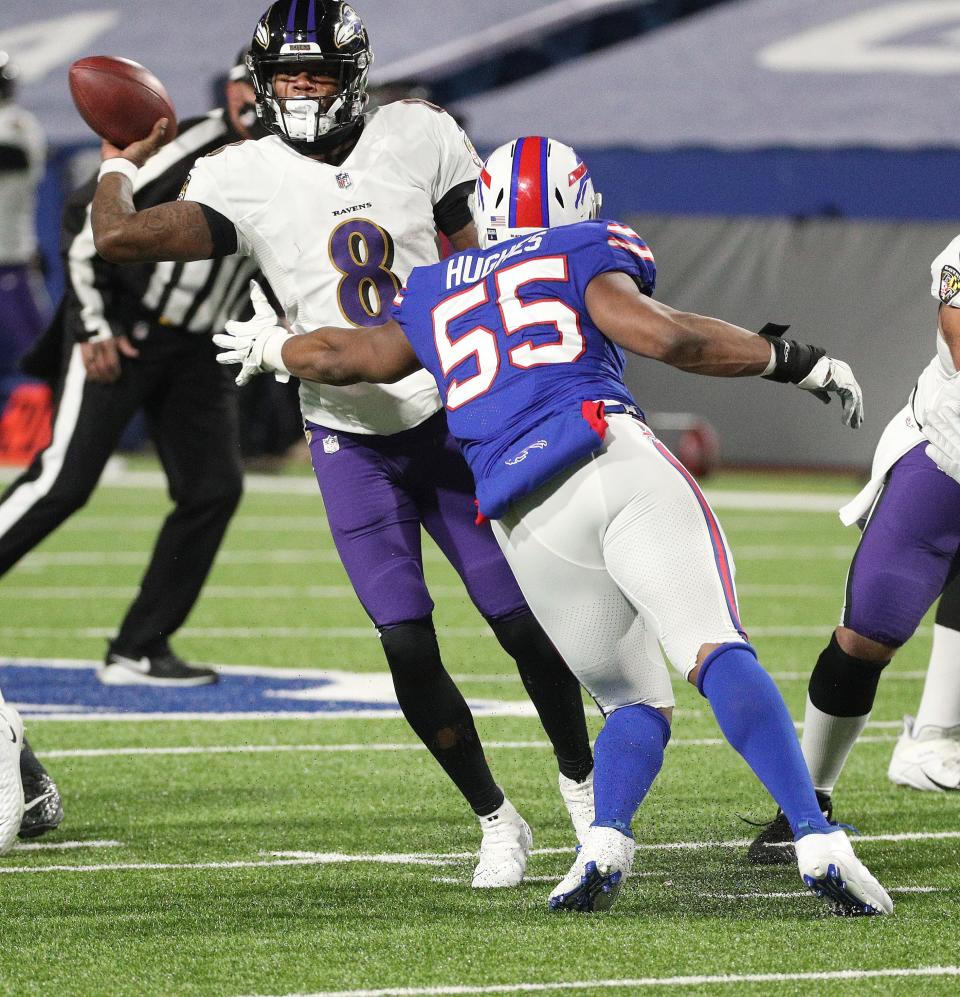 Ravens quarterback Lamar Jackson has to get rid of the ball as he is pressured by Bills Jerry Hughes. 