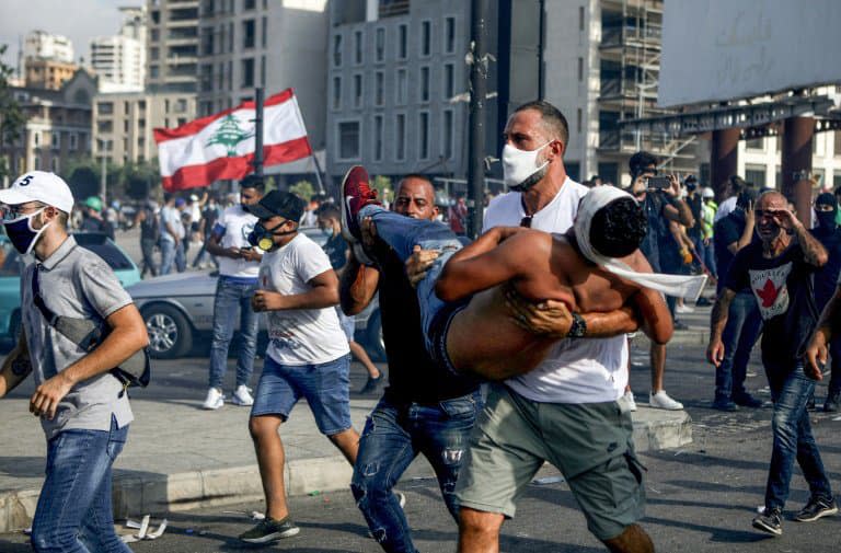 La star du basketball au Liban Fadi al-Khatib transporte en courtant un manifestant blessé lors des manifestations à Beyrouth contre le pouvoir, le 8 août 2020  - PATRICK BAZ © 2019 AFP