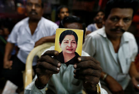 A supporter of Tamil Nadu Chief Minister Jayalalithaa Jayaraman holds her photo at the AIADMK party office in Mumbai, India, December 5, 2016. REUTERS/Danish Siddiqui