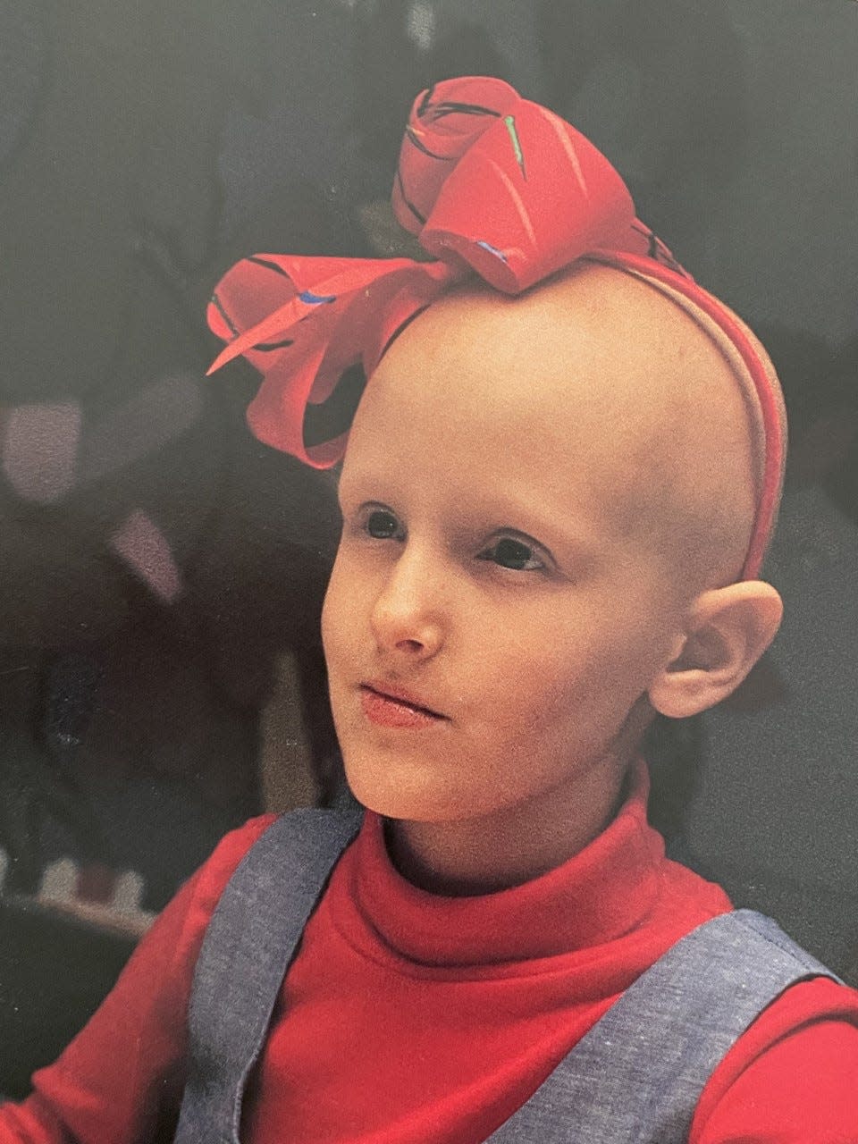 Laura Shinn as a child wearing a red bow on her head