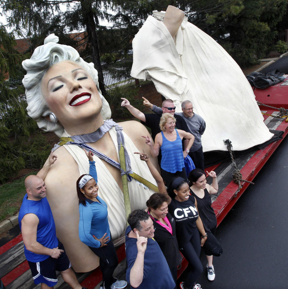 A group gathers to have their photograph taken with parts of a 26-foot-tall, 34,000-pound statue named "Forever Marilyn" in Hamilton, N.J., Tuesday, April 8, 2014. The sculpture depicting Marilyn Monroe in her memorable billowing skirt pose from the "The Seven Year Itch" is part of an exhibit at the Grounds for Sculpture in Hamilton, honoring its designer, Seward Johnson. (AP Photo/Mel Evans)