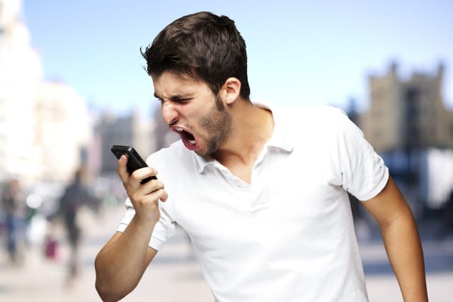 portrait of an angry young man shouting using a mobile at a crowded street