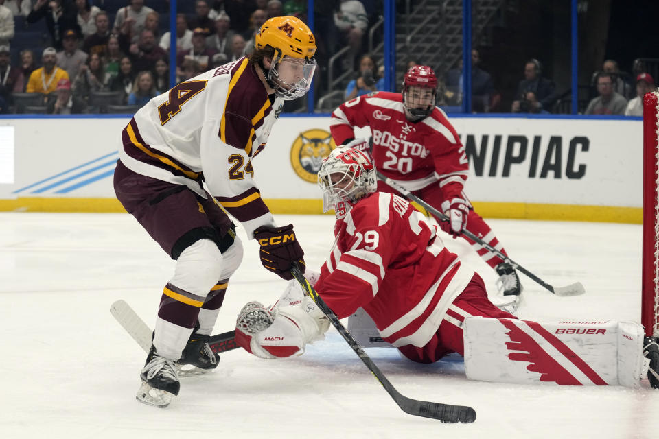 Boston University goaltender Drew Commesso (29) makes a pad save on a shot by Minnesota forward Jaxon Nelson (24) during the first period of an NCAA semifinal game in the Frozen Four college hockey tournament Thursday, April 6, 2023, in Tampa, Fla. (AP Photo/Chris O'Meara)