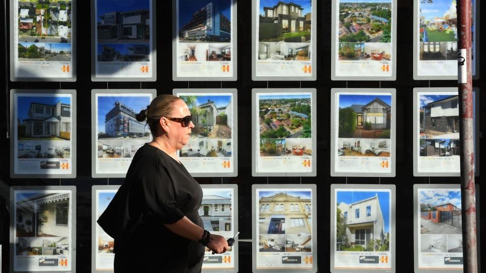 woman in front of real estate listings