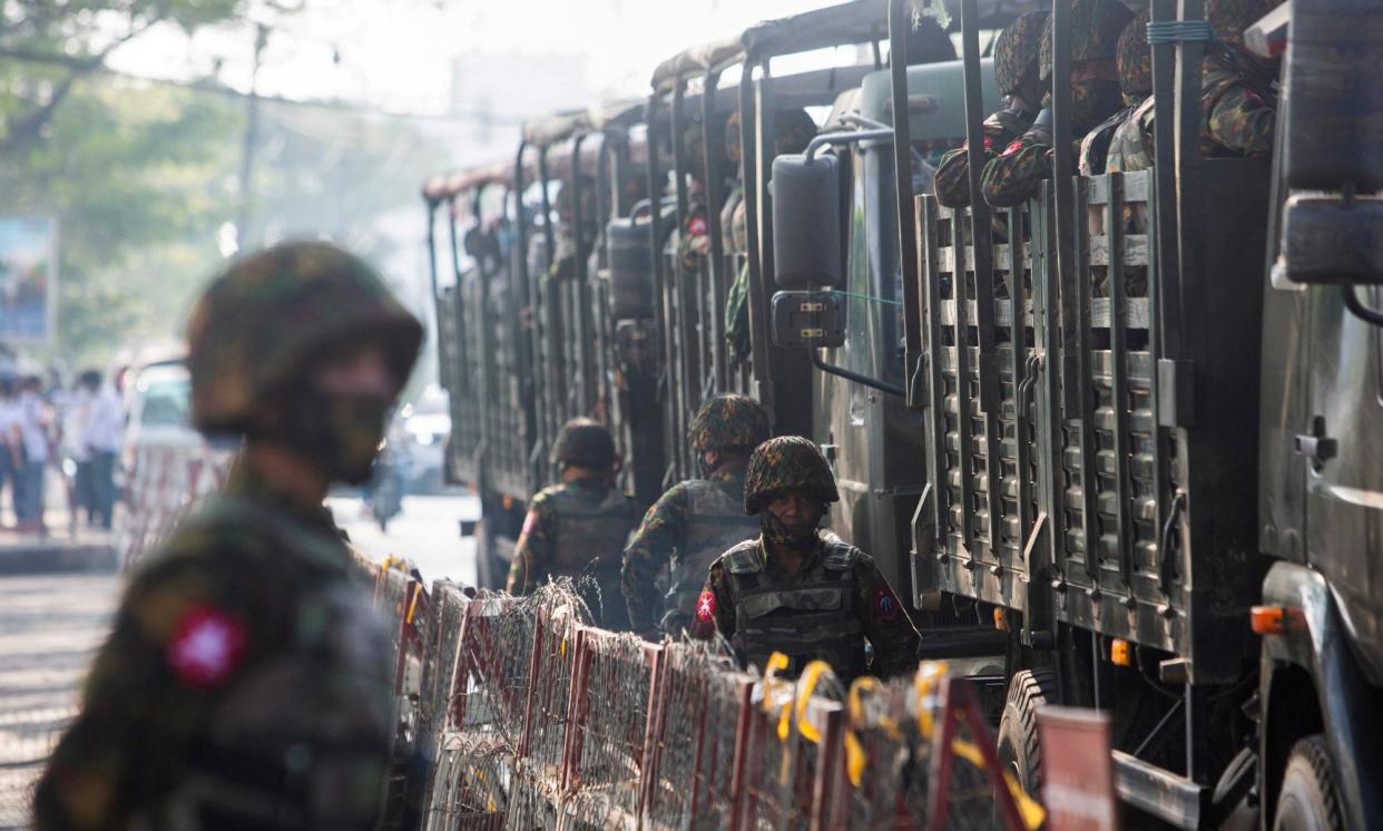 <span>Soldiers stand next to military vehicles as people gather in Yangon to protest against the Myanmar military coup, 15 February 2021.</span><span>Photograph: Reuters</span>
