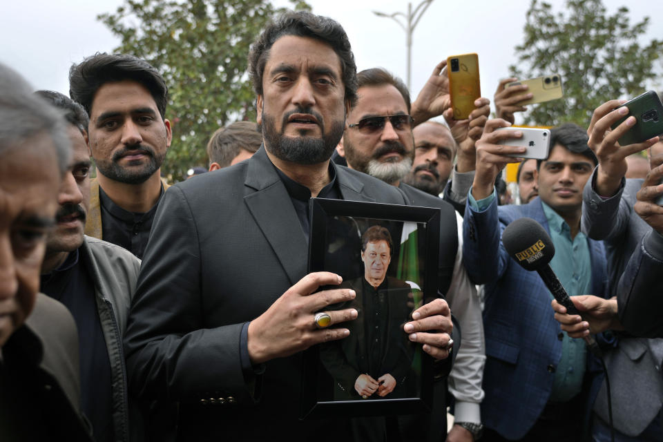 Pakistan's newly elected lawmaker Shehryar Afridi, center, displays a picture of his leader and imprisoned former Prime Minister Imran Khan as he arrives to attend the opening session of parliament, in Islamabad, Pakistan, Thursday, Feb. 29, 2024. Pakistan's National Assembly swore in newly elected members on Thursday in a chaotic scene, as allies of jailed former Premier Khan protested what they claim was a rigged election. (AP Photo/Anjum Naveed)