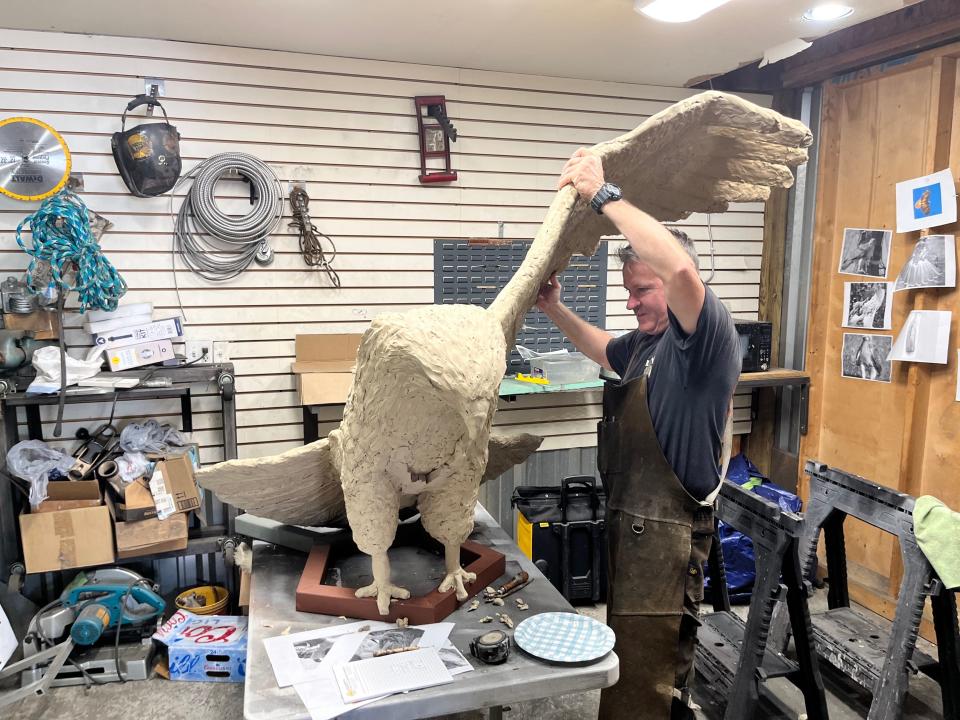 Ryan Feeney, of Indy Art Forge, holds up a wing of a red-tailed hawk sculpture that will eventually be part of a roundabout art piece at the intersection of 106th Street and College Avenue in Carmel's Home Place neighborhood.