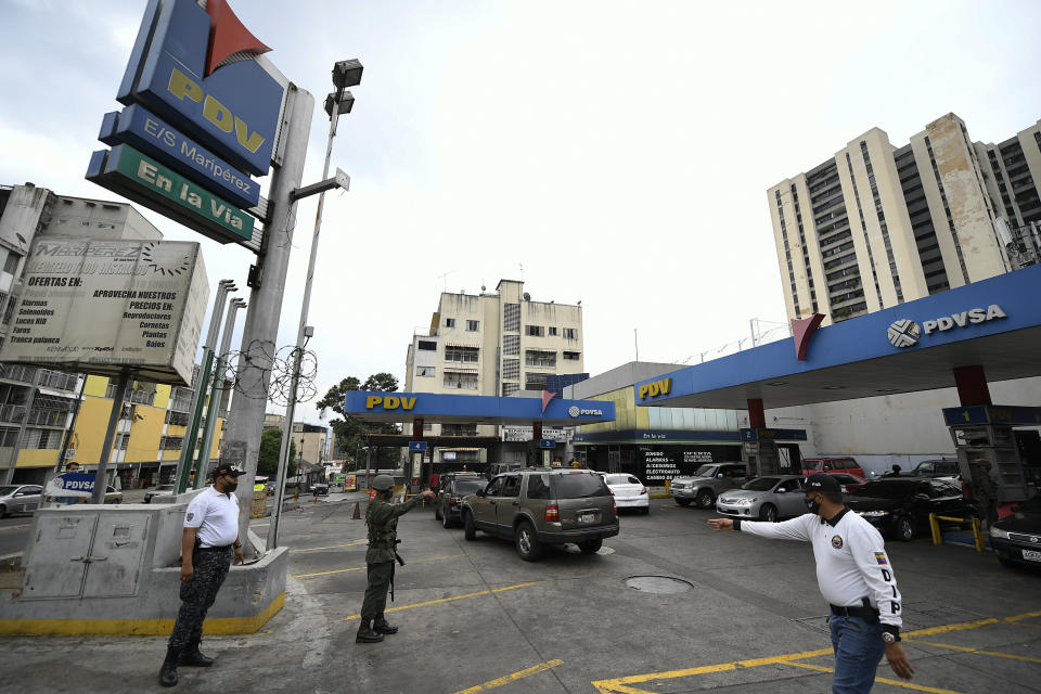 A soldier stands guard at a PDVSA state oil company gas station where drivers wait in line for hours to fill up in Caracas, Venezuela, Monday, May 25, 2020. The first of five tankers loaded with gasoline sent from Iran this week is expected to temporarily ease Venezuela's fuel crunch while defying Trump administration sanctions targeting the two U.S. foes. (AP Photo/Matias Delacroix)