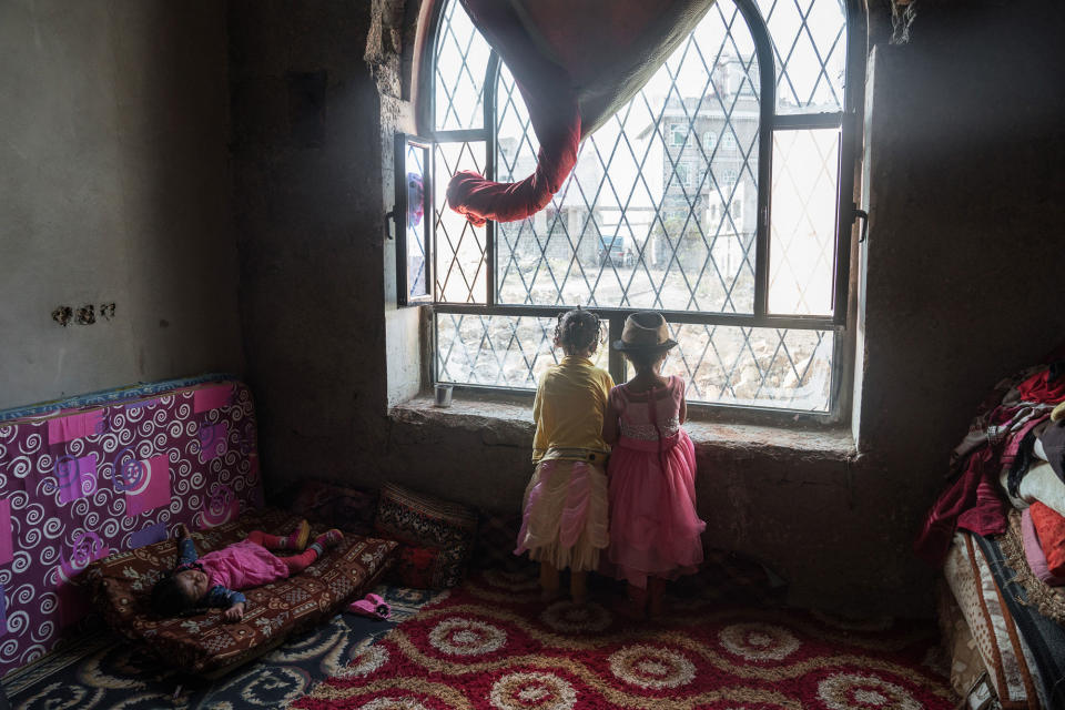 <p>Al Abthi building, Ibb City, Yemen, April 21, 2017: Children peer out of a window in a former government building in the suburbs of Ibb. The building was provided by local authorities to house 53 displaced families who fled here from Taizz after heavy fighting flared up in the summer of 2015. The building has no electricity or running water. The displaced families installed solar panels on the roof of the building to provide power for rudimentary lighting at night. Many of the children help their parents by collecting water and tending to the younger children in the building. (Photograph by Giles Clarke for UN OCHA/Getty Images) </p>
