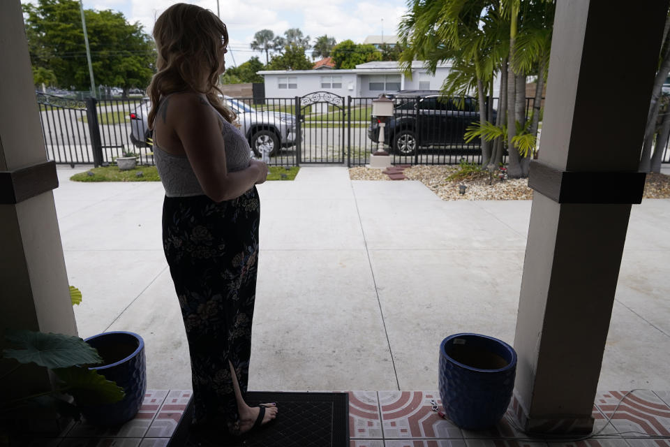 Nicole Russell looks out from her porch, Friday, March 12, 2021, in Kendall, Fla. Because of the pandemic, Nicole because fearful of leaving her home and retreated to her bedroom for days at a time. While some felt restricted by the confinement of home "caves", others found a sense of safety and comfort, becoming increasingly accustomed to the isolation. (AP Photo/Marta Lavandier)