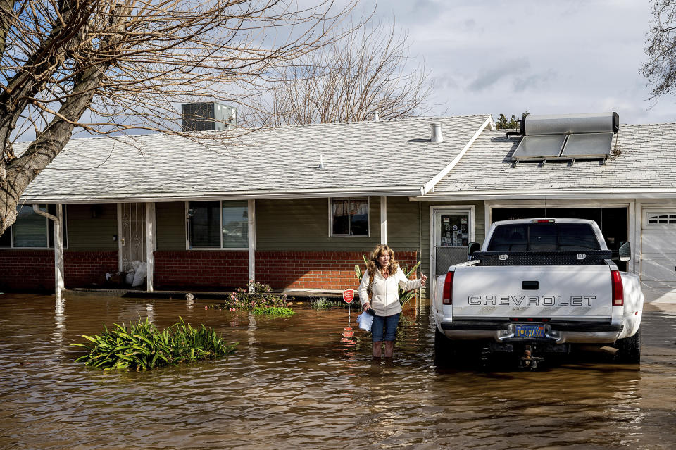 Kim Ochoa leaves her Merced, Calif., home, which is surrounded by floodwaters, as storms continue to batter the state on Tuesday, Jan. 10, 2023. (AP Photo/Noah Berger)