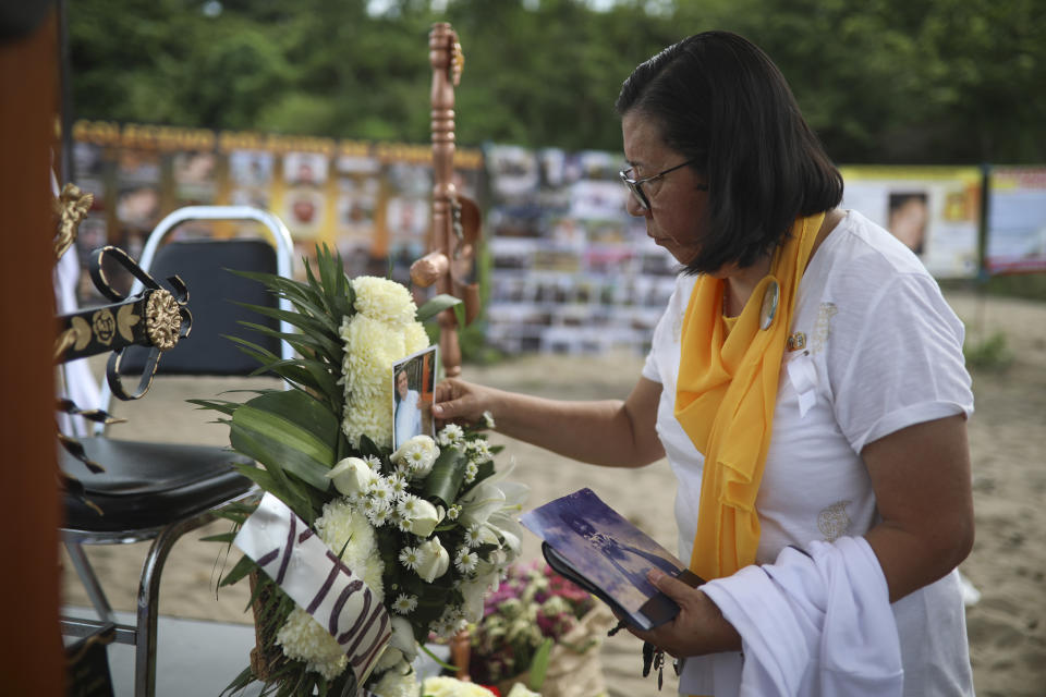 Martha Elba Jimenez, mother of Oscar Jimenez who is missing, places his photo on an altar after a Mass was celebrated at the site where almost 300 human remains were found in clandestine graves in Colinas de Santa Fe, Mexico, Monday, Oct. 15, 2018. The Mass was held one day before the Solecito Collective is to be honored by Notre Dame for its work locating the remains of missing people in Veracruz state. The Solecito Collective is made up people searching for their missing loved ones. (AP Photo/Felix Marquez)