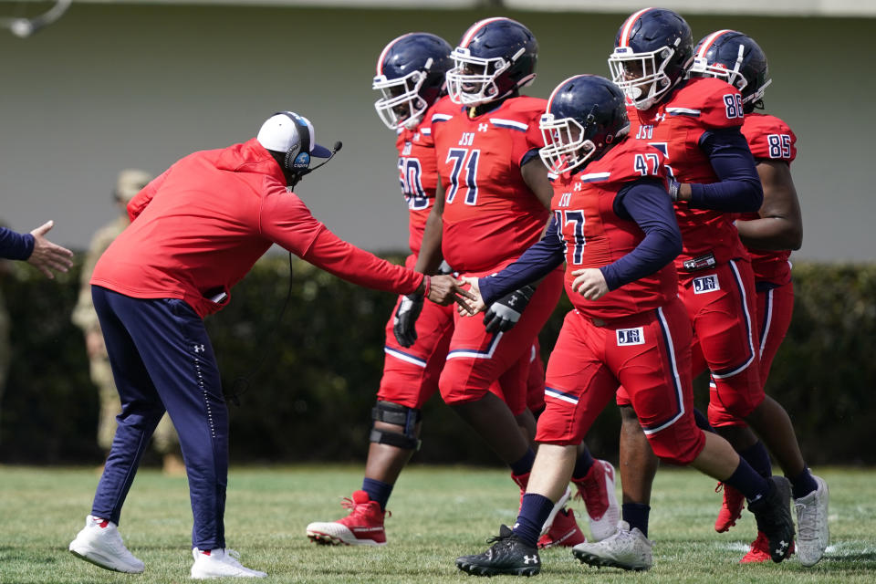 Coach Deion Sanders congratulates his team as they come off the field during the first half of an NCAA college football game against Edward Waters in Jackson, Miss., Sunday, Feb. 21, 2021. The game marked the coaching debut of Sanders. (AP Photo/Rogelio V. Solis)