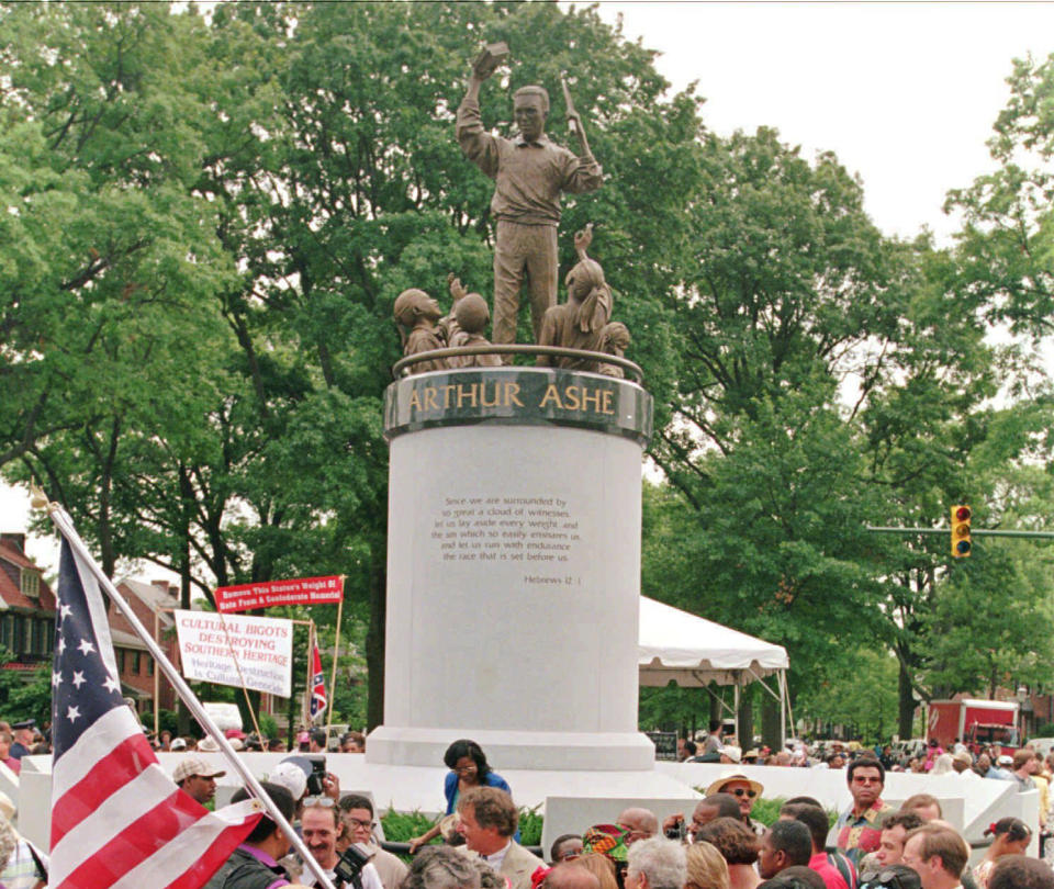 FILE - In this July 10, 1996 file photo, a crowd gathers at the base of the Arthur Ashe Monument after the ceremony dedicating the statue on Monument Avenue in Richmond, Va. The statue of the African American tennis legend has been vandalized with the words “White Lives Matter.” Richmond Police said they were alerted to the vandalism Wednesday, June 17, 2020. Police say red paint on the statue itself was already being cleaned off by community members. (AP Photo/Steve Helber)