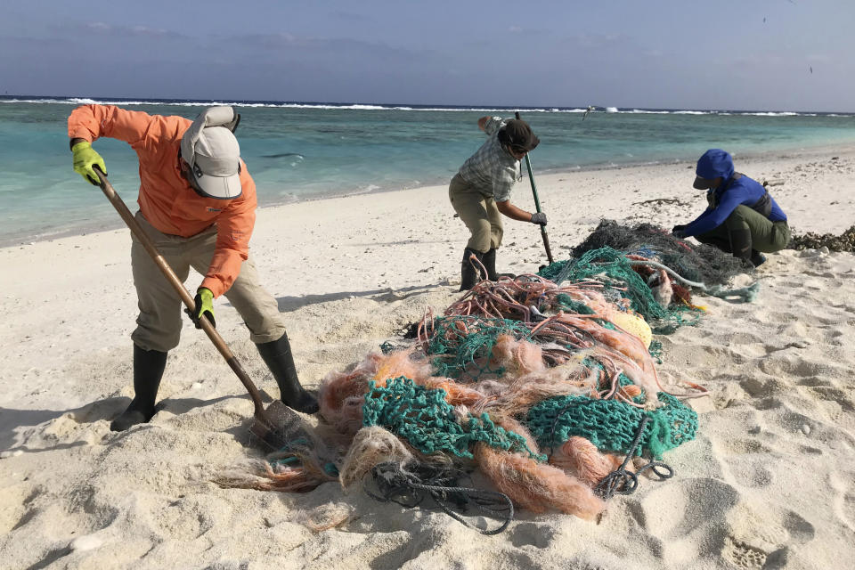 In this March 12, 2020, photo provided by Matt Saunter, Matt Butschek II, left, Charlie Thomas, center, and Naomi Worcester clean up fishing nets at a field camp on Kure Atoll in the Northwestern Hawaiian Islands. Cut off from the rest of the planet since February, the environmental field workers are back, re-emerging into a society changed by the coronavirus outbreak. (Matt Saunter/Hawaii Department of Land and Natural Resources via AP)