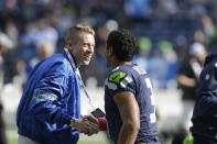 FILE - In this Oct. 13, 2013, file photo, Seattle hip hop and rap singer Macklemore, left, greets Seattle Seahawks quarterback Russell Wilson before an NFL football game between the Seahawks and Tennessee Titans in Seattle. The MLS soccer Seattle Sounders team announced Tuesday, Aug. 13, 2019, that they are adding Macklemore and Wilson to club's ownership group, along with several others as Hollywood producer Joe Roth leaves the franchise.(AP Photo/Elaine Thompson, File)