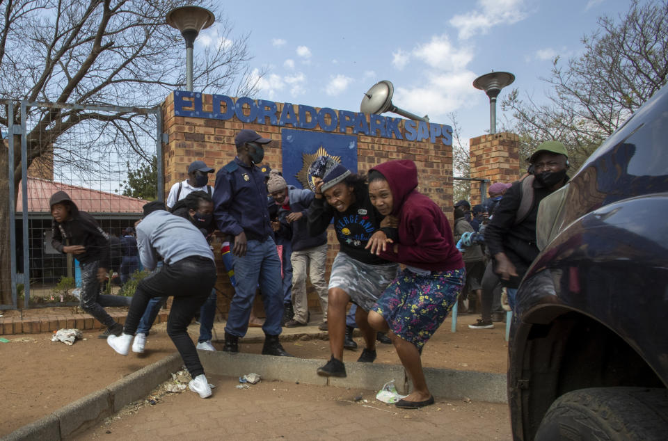 Protesters run for cover as they clash with police at Eldorado Park police station in Johannesburg, South Africa, Thursday, Aug. 27, 2020. Residents from the township, south of Johannesburg are demanding justice for a teenager shot and killed, allegedly at the hands of police Wednesday. (AP Photo/Themba Hadebe)