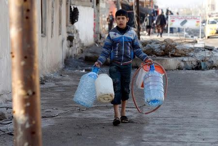 A boy collects water at al Zohour area in Mosul, Iraq, January 23, 2017. REUTERS/Muhammad