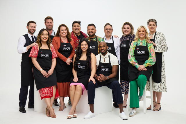 The Group 1 contestants for My Kitchen Rules 2022 stand and sit together in black MKR aprons